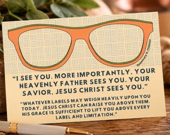 May include: A rectangular card featuring a large orange eyeglass frame graphic on a light tan background with a woven pattern. The text reads: I SEE YOU. MORE IMPORTANTLY, YOUR HEAVENLY FATHER SEES YOU. YOUR SAVIOR, JESUS CHRIST SEES YOU.