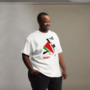 May include: A white short-sleeve t-shirt featuring a geometric graphic design in red, black, and green. The text "FOR PALESTINE TO LIVE" is printed in black above the graphic, and "IMPERIALISM MUST DIE" is printed in red below the design.