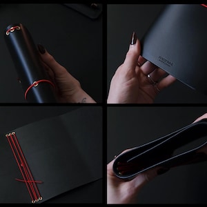 May include: Black leather journal with red stitching and accents. The journal is closed with a red elastic band and features gold-colored eyelets. The journal is shown open and closed, displaying the interior pages and exterior details.