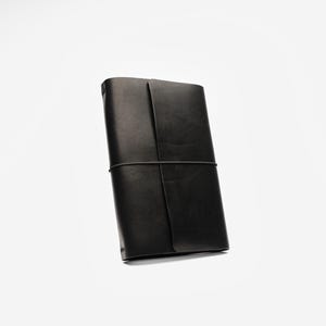 May include: A black leather journal with a wraparound elastic closure. The journal is rectangular and appears to be closed. The leather has a matte finish. The journal is set against a white background.