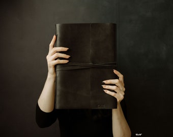 May include: A black leather-bound journal with a simple, elegant design. The journal is tied closed with a black ribbon and has the word "Milk" embossed on the front cover. The journal measures 10x14 inches.