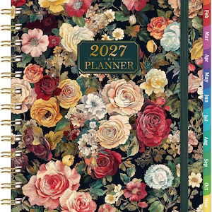 May include: A 2027 planner with a dark background featuring a dense floral pattern of red, yellow, pink, and white roses. The planner has a gold-colored spiral binding on the left side, a dark green elastic closure, and monthly tabs along the right edge.