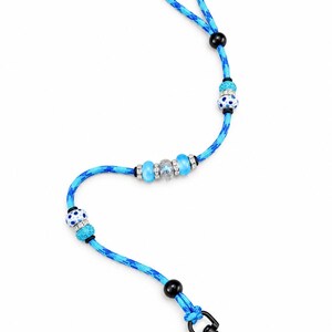 May include: A blue camouflage patterned rope leash featuring a series of decorative beads. The beads include solid light blue, white with blue polka dots, and clear glitter-filled spheres, all accented with small silver-toned rhinestone spacers.