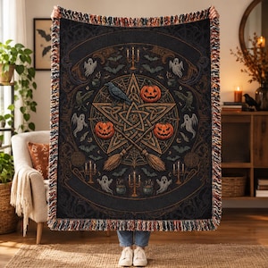 May include: A woven throw blanket featuring a dark background with a central pentagram, three jack-o'-lanterns, a black raven, two crossed broomsticks, ghosts, bats, and candelabras. The blanket has a fringed edge with multi-colored threads.