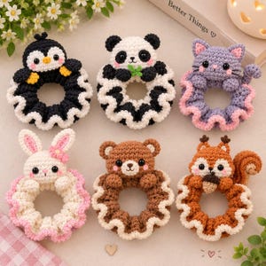 May include: Six crocheted hair scrunchies featuring animal designs: a black and white penguin, a black and white panda, a purple cat, a white rabbit with a pink flower, a brown bear, and an orange squirrel holding an acorn, all with ruffled edges.