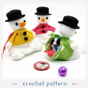 May include: Crocheted snowman figures in yellow, pink, and green jackets, each wearing a black top hat. One snowman holds a pouch filled with candy. A red penguin-themed chocolate and a purple wrapped candy are also visible. The text "crochet pattern" is at the bottom.