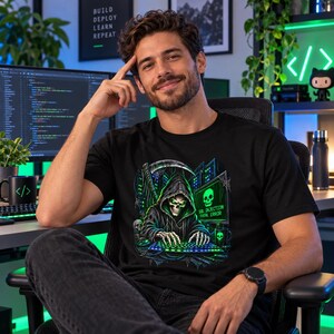 May include: A black t-shirt featuring a graphic of a hooded skeleton hacker sitting at a computer with a scythe in the background. The screen displays a skull icon and the text SQL INJECTION FATAL ERROR in bright green against a dark background.