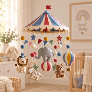 Puede incluir: Un móvil de cuna con temática de circo que presenta un dosel de fieltro en rojo, azul y crema. Los elementos colgantes incluyen un león, una cebra sobre una luna creciente, un elefante sobre una pelota, un oso en un columpio, un globo aerostático y estrellas.