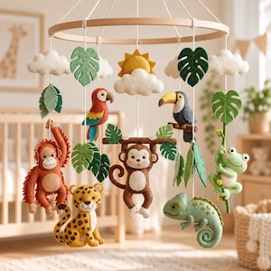 May include: A nursery mobile featuring felt jungle animals including an orangutan, a leopard, a monkey, a toucan, a parrot, and a frog, suspended from a wooden ring with felt clouds, a sun, and green monstera leaves on white strings.