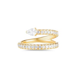 Op de afbeelding: Een gouden bypass-ring met een doorlopende band van kleine ronde witte stenen en een enkele peervormige witte steen aan één uiteinde. De metalen band heeft een gepolijste geelgouden afwerking en de stenen zijn over de gehele lengte van de ring gezet.
