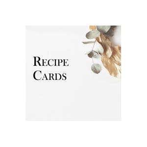 May include: White card with the text "RECIPE CARDS" in black font. A sprig of eucalyptus with dried leaves is in the upper right corner of the card.