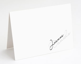 May include: White place card with the name "Joanne Daniels" written in black and gray cursive script.