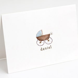 May include: A white card with a brown and blue baby carriage illustration and the name "daniel" written below it.