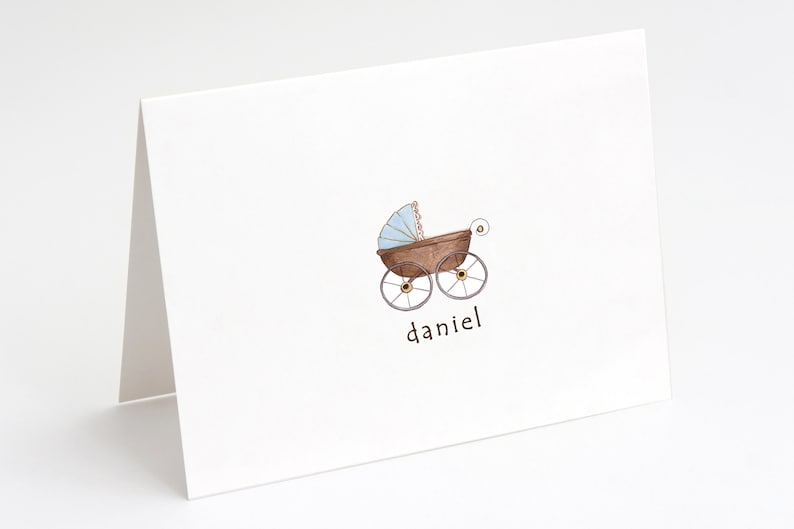 May include: A white card with a brown and blue baby carriage illustration and the name "daniel" written below it.