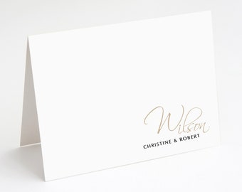 May include: White card with the text "Wilson" in gold script and "Christine & Robert" in black text below.
