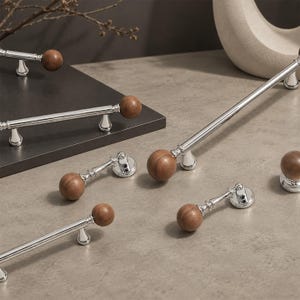May include: A collection of cabinet hardware featuring polished chrome metal bars and bases paired with smooth, round, natural brown wooden knobs. The set includes various lengths of drawer pulls and individual round knobs with a metallic finish.