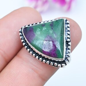 May include: A triangular ring featuring a polished green and purple zoisite stone set in a sterling silver band. The metal setting displays a decorative beaded edge detail surrounding the gemstone, which exhibits natural colour variations.