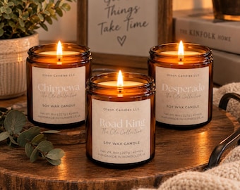 May include: Three amber glass jar soy wax candles with lit wicks. Labels read Olson Candles LLC, The Ole Collection, and the scent names Chippewa, Road King, and Desperado. Each label states Net Wt. 8oz | 227g | 45+Hrs, Handmade in Humboldt, IA.