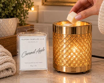 May include: A cylindrical gold wax warmer with a geometric diamond cutout pattern and a clear plastic package of Olson Candles LLC Caramel Apple hand poured soy wax melts, weighing 85g, placed on a countertop.