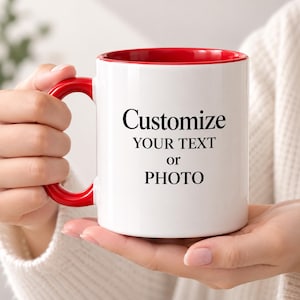 Puede incluir: Una taza de cerámica blanca con asa e interior de color rojo brillante. El exterior presenta el texto impreso en negro Customize YOUR TEXT or PHOTO. La taza tiene un cuerpo cilíndrico y un asa curva, diseñada para bebidas calientes.