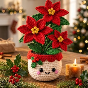 May include: A crocheted poinsettia plant with vibrant red petals and yellow centers, potted in a cream-colored crocheted container featuring a smiling face with black eyes and pink cheeks, accented by a small red berry and green leaf detail.