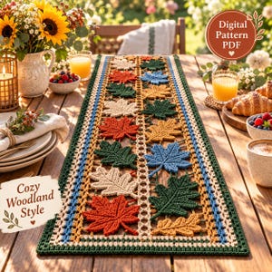 May include: A rectangular crochet table runner featuring a repeating pattern of autumn leaves in shades of orange, red, green, yellow, and cream. The runner has a decorative border and is displayed on a wooden table. Text reads Digital Pattern PDF.
