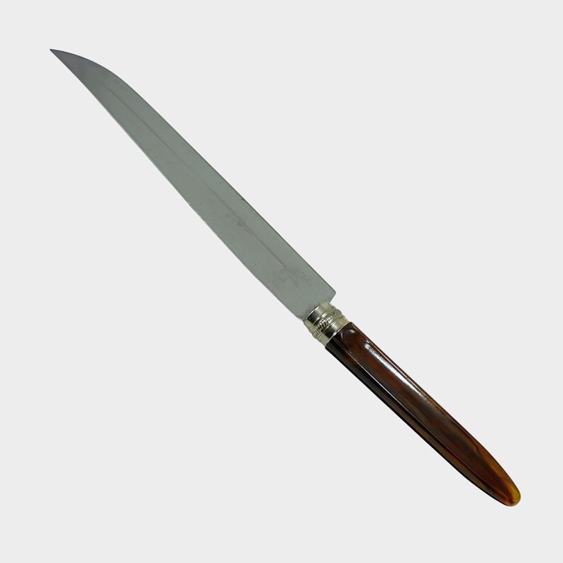 Puede incluir: Un cuchillo largo de acero inoxidable con mango marr&oacute;n y detalles plateados. La hoja es afilada y angulada, y el mango es de color marr&oacute;n oscuro. El cuchillo est&aacute; dise&ntilde;ado para cortar y rebanar.