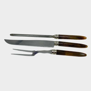 Puede incluir: Un juego de trinchar de tres piezas que incluye un cuchillo, un tenedor y un afilador. Las hojas y el acero inoxidable se combinan con mangos marrones y beige. Los mangos est&aacute;n acentuados con metal plateado.