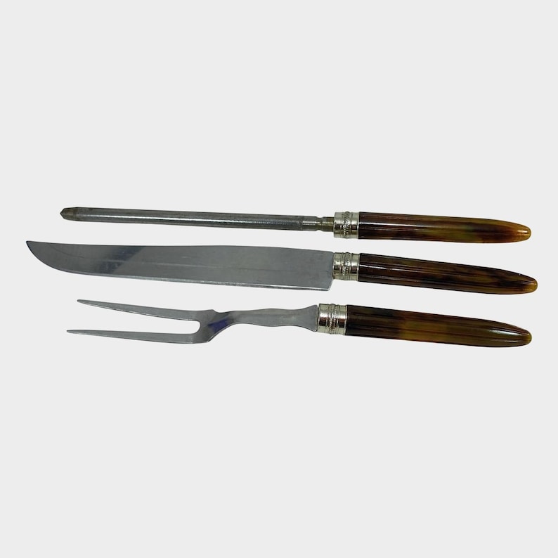 Puede incluir: Un juego de trinchar de tres piezas que incluye un cuchillo, un tenedor y un afilador. Las hojas y el acero inoxidable se combinan con mangos marrones y beige. Los mangos est&aacute;n acentuados con metal plateado.