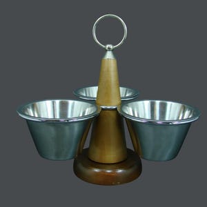 May include: A three-tiered serving piece with a wooden base and central column. It features three stainless steel bowls and a ring handle at the top. The wood has a natural finish, and the bowls have a silver rim.