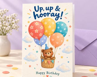 Könnte beinhalten: Eine druckbare Geburtstagskarte mit einem braunen Bären in einem Weidenkorb, der an bunten Luftballons befestigt ist, mit dem Text Up, up & hooray! und Happy Birthday. Die Karte ist 5 x 7 Zoll groß und zeigt eine Illustration von Ballons.