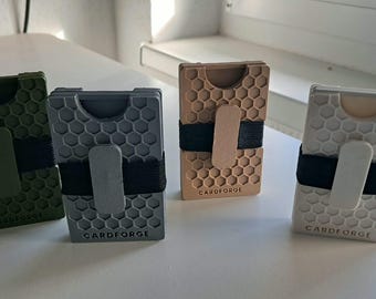 Könnte beinhalten: Vier rechteckige Kartenhalter mit Wabenmuster auf der Vorderseite. Jeder Halter verfügt über ein schwarzes Gummiband mit einem farblich passenden Clip und dem eingeprägten Schriftzug CARDFORGE an der Unterseite. Die Farben sind Olivgrün, Grau, Beige und Weiß.