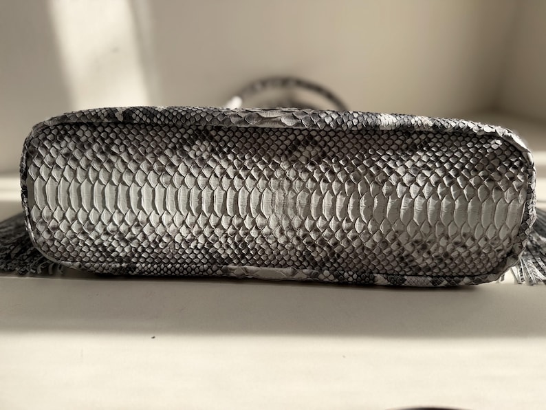 May include: A rectangular handbag base featuring a monochromatic snakeskin pattern in shades of gray, black, and white. The surface displays a textured, overlapping scale design with a distinct central panel of larger scales and smaller scales on the sides.