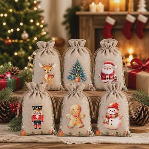 May include: Six small hessian drawstring gift bags featuring festive holiday illustrations. The designs include a fawn, a decorated Christmas tree, Santa Claus, a nutcracker, a gingerbread man, and a snowman, all printed on a natural tan fabric.