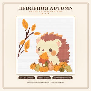 Könnte beinhalten: Ein Kreuzstichmuster mit dem Titel HEDGEHOG AUTUMN, das einen Igel mit einem Blatt zeigt, umgeben von Kürbissen und einem Zweig mit orangefarbenen Blättern. Das Design umfasst 120 x 121 Stiche, 14 DMC-Farben und ist als PDF-Download erhältlich.