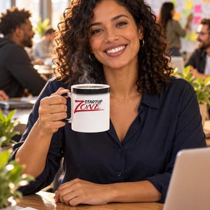 Peut inclure: Un mug en céramique blanche avec une anse et un bord noirs, portant l'inscription rouge et noire "STARTUP ZONE" sur le devant. Le mug contient une boisson chaude fumante et la surface extérieure présente un dégradé de couleur subtil.