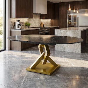May include: An oval dining table featuring a black marble top with white veining. The table is supported by a geometric, gold-colored metal base consisting of interconnected angular segments resting on a flat, square gold-colored metal plate.