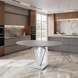 Peut inclure: Une table à manger ovale avec un plateau gris clair aspect pierre et un pied central géométrique blanc. La table présente une structure de support centrale avec des pieds en métal blanc inclinés reliés à une base carrée plate.