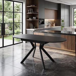 Puede incluir: Una mesa de comedor ovalada en negro mate con una superficie de tablero lisa y una base geométrica distintiva con cuatro patas anguladas que se unen en puntos centrales, proporcionando una base estable para la estructura.