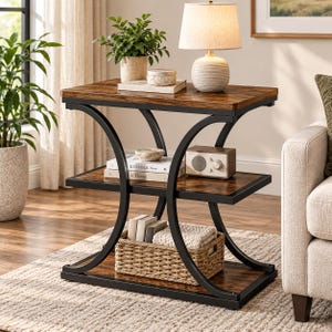 May include: A three-tier side table featuring a dark wood grain finish on the rectangular shelves and a black metal frame with curved side supports. The table holds a lamp, books, a small radio, and a woven basket on the bottom shelf.