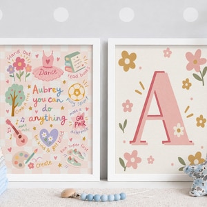 May include: Two framed wall art prints. The left print features a pink checkered background with illustrations of a tutu, books, soccer ball, guitar, and paint palette, with the text "Aubrey you can do anything". The right print shows a large pink letter A.