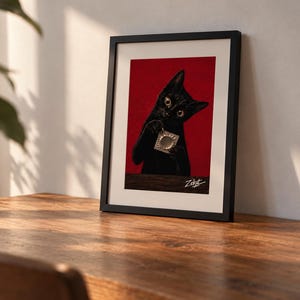 Peut inclure: Une impression d'art encadrée représentant un chat noir aux yeux écarquillés sur un fond rouge uni. Le chat tient un petit sachet en aluminium carré de couleur argentée entre ses pattes. La signature Zekat est inscrite en blanc en bas à droite.