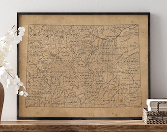 May include: A framed vintage-style map of Colorado printed on tan paper with black ink. The map displays county boundaries, river systems, and labels for various counties including Moffat, Larimer, and Las Animas, all enclosed in a black frame.