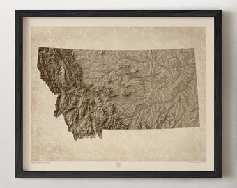 May include: A framed topographic map of Montana printed in shades of brown and beige. The map features detailed relief shading of the state's mountainous terrain and plains, set against a textured, parchment-like background within a black frame.
