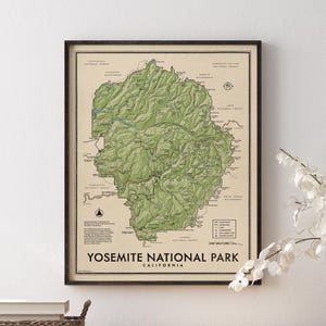May include: A framed topographic map of Yosemite National Park in California, featuring detailed green terrain shading, black contour lines, and labeled landmarks. The print includes a legend, compass rose, and the text Yosemite National Park California.