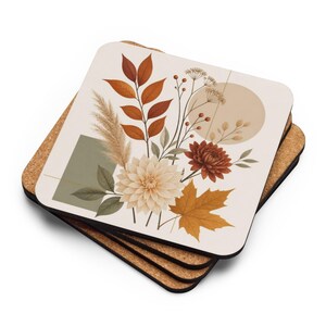 Könnte beinhalten: Ein Stapel quadratischer Untersetzer mit Korkunterseite und weißer Oberseite, bedruckt mit einer botanischen Illustration aus Herbstblättern, Pampasgras und Dahlien in Orange-, Braun- und Cremetönen, ergänzt durch geometrische Formen in Salbeigrün.