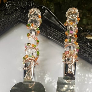 May include: Two cake serving utensils with clear crystal handles adorned with copper wire and colorful beads in shades of orange, green, pink, and gold. The blades are silver and the handles are embellished with a decorative wire design.