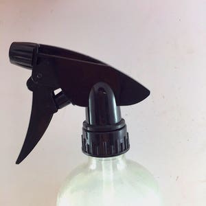May include: Black plastic spray bottle with a trigger nozzle. The bottle is clear and has a textured surface.