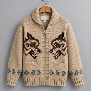 May include: A beige knit zip-up cardigan featuring a shawl collar and a full-length front zipper. The garment displays two symmetrical brown and black wolf head motifs on the chest, with blue paw print patterns along the hem and cuffs.