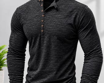 May include: A long-sleeve henley shirt in a dark charcoal gray heathered fabric. The shirt features a mandarin collar and a partial front placket with six small, round, light brown buttons. The fabric has a subtle, textured, mottled appearance.